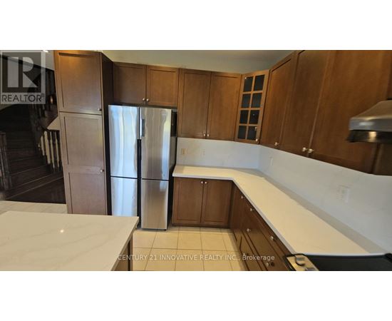A kitchen with wooden cabinets and a stainless steel refrigerator.