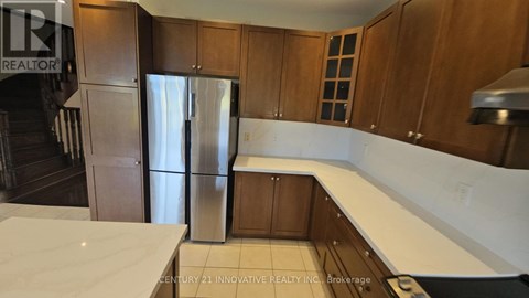 A kitchen with wooden cabinets and a stainless steel refrigerator.