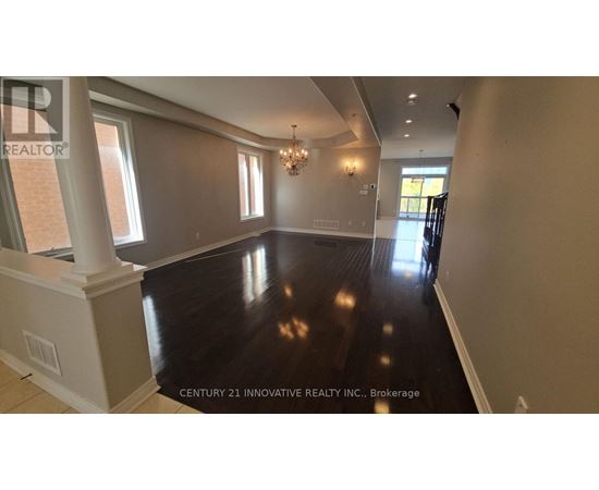 A spacious room with wooden floors and a chandelier.