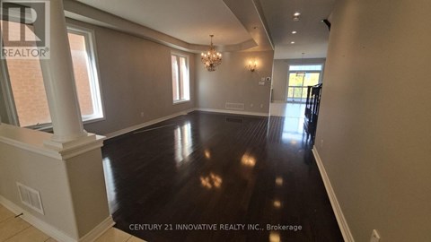 A spacious room with wooden floors and a chandelier.