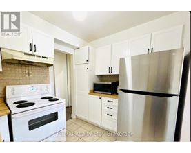 A kitchen with white cabinets and a stainless steel refrigerator.