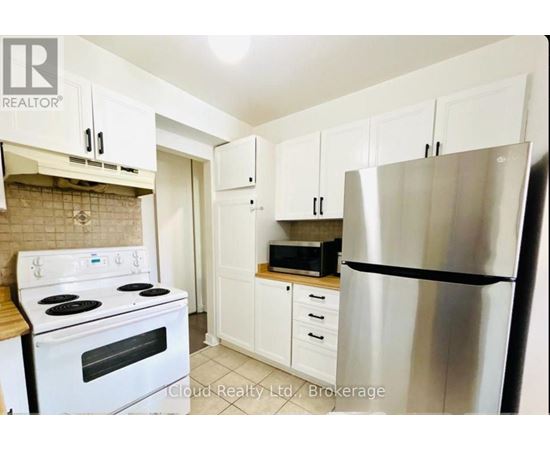 A kitchen with white cabinets and a stainless steel refrigerator.