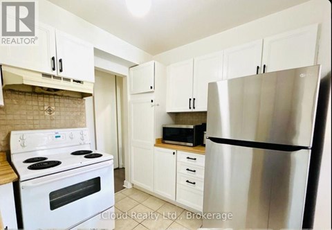 A kitchen with white cabinets and a stainless steel refrigerator.
