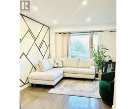 A white couch with a green chair and a rug in front of a window.