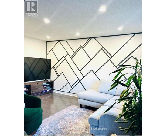 A living room with a white sofa and a black and white geometric wall design.