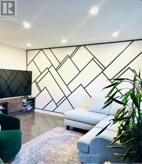 A living room with a white sofa and a black and white geometric wall design.