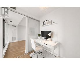 A white desk with a computer and lamp in a room with a white chair and a white wall.