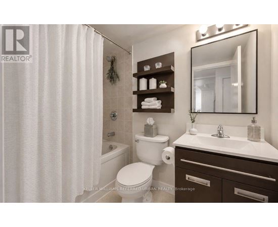A white toilet sits in a bathroom with a white shower curtain.