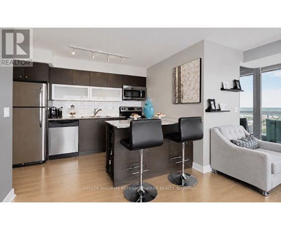 A modern kitchen with a refrigerator, microwave, and a dining table with chairs.