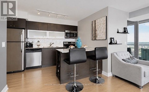 A modern kitchen with a refrigerator, microwave, and a dining table with chairs.