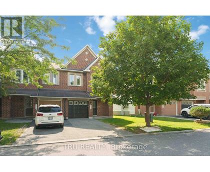 A white car is parked in front of a brick house.