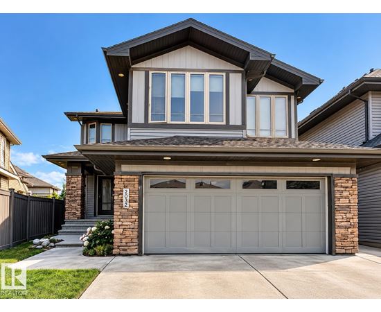 A modern house with a grey garage door and a stone pillar.