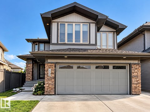 A modern house with a grey garage door and a stone pillar.