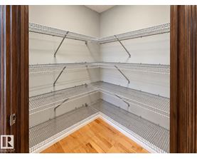 A walk-in closet with shelving and a wooden floor.