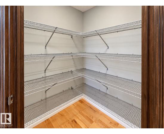 A walk-in closet with shelving and a wooden floor.