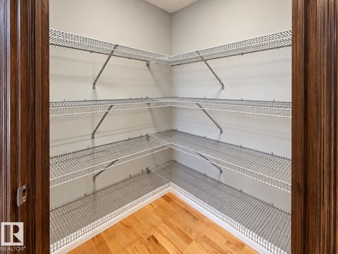 A walk-in closet with shelving and a wooden floor.