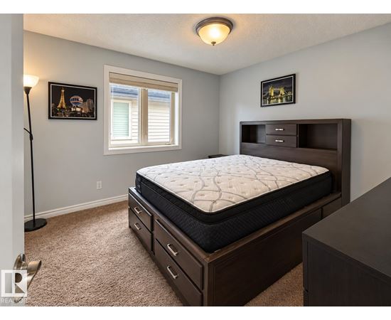 A bedroom with a large bed and a window with blinds.