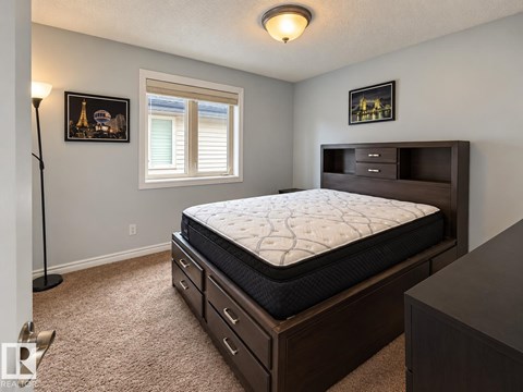 A bedroom with a large bed and a window with blinds.
