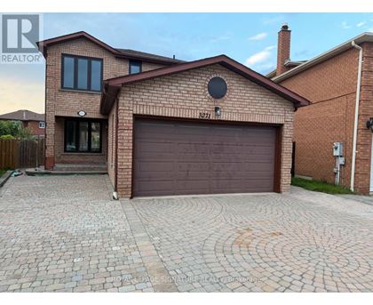 A brick house with a garage and a driveway in front.