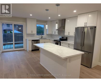 A kitchen with white cabinets and a marble island.