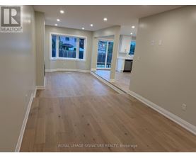 A spacious room with wooden flooring and a large window overlooking a balcony.