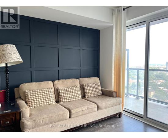 A living room with a beige couch and a lamp on a side table.