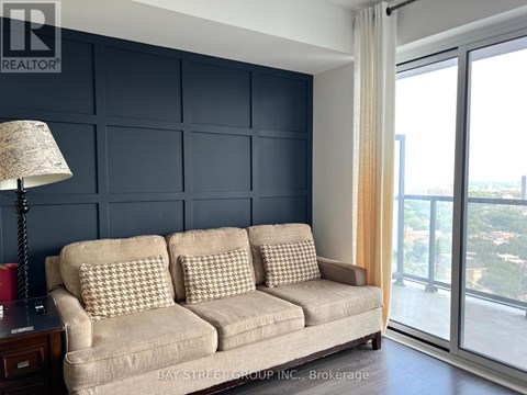 A living room with a beige couch and a lamp on a side table.