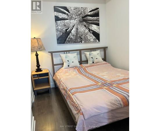 A bedroom with a bed, a lamp, and a picture on the wall.