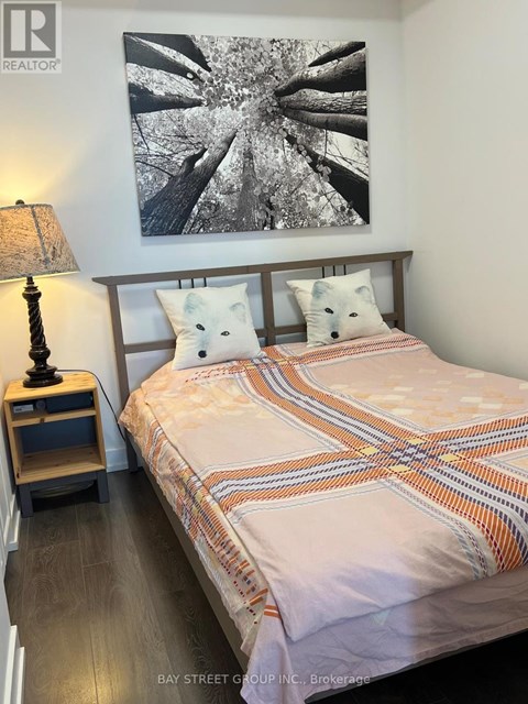 A bedroom with a bed, a lamp, and a picture on the wall.