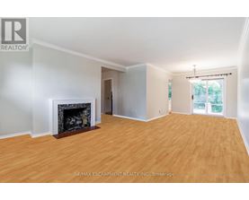 A large, empty room with a fireplace and wood flooring.