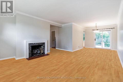 A large, empty room with a fireplace and wood flooring.