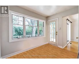 A room with a door, windows and wooden floors.