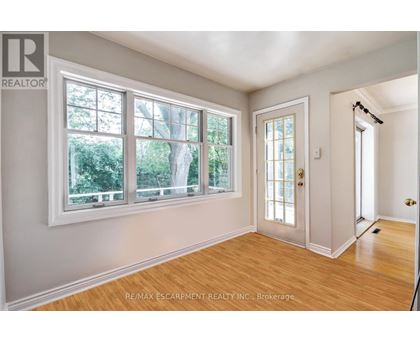 A room with a door, windows and wooden floors.