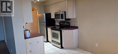 A kitchen with white cabinets and a black fridge.