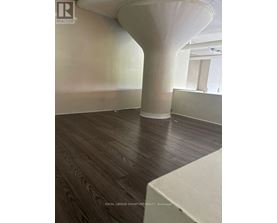 A room with a white column and wooden flooring.