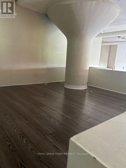 A room with a white column and wooden flooring.