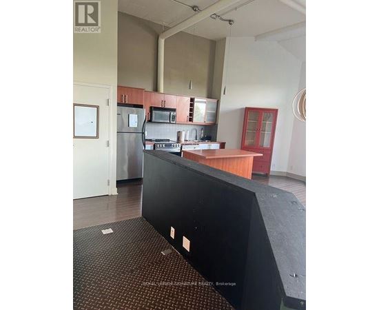 A kitchen area with a black counter and a fridge.