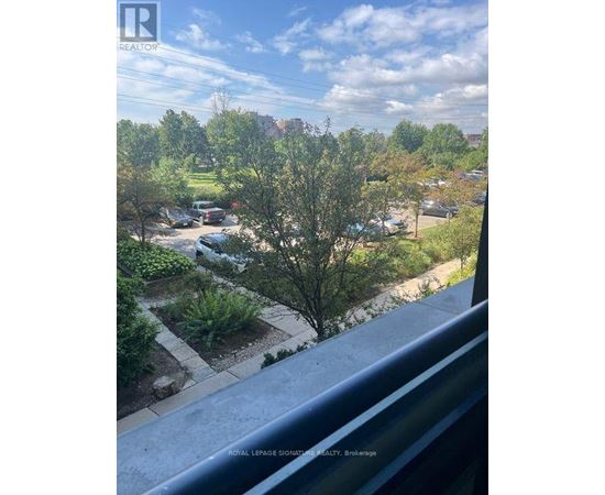 A view from a balcony looking out over a residential area with trees and cars.