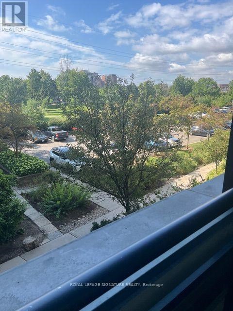 A view from a balcony looking out over a residential area with trees and cars.