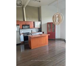 A kitchen with a wooden island and a hanging light fixture.