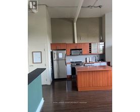 A kitchen with a refrigerator, oven, and microwave.