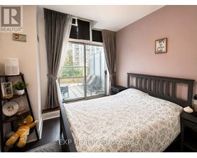 A bedroom with a large bed and a window with curtains.