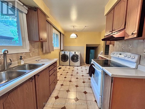 A kitchen with a white stove top oven and a white sink.