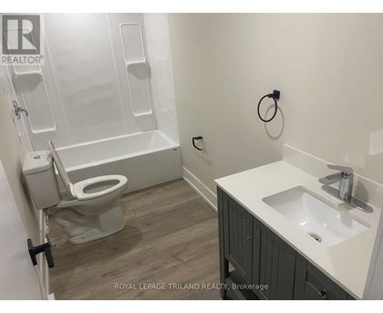 A white sink is on a counter next to a toilet.