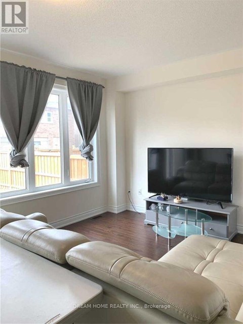 A living room with a white couch and a flat screen TV.