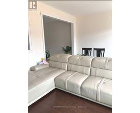 A white leather sofa in a room with a wooden floor.