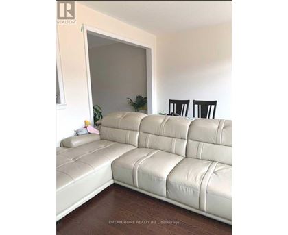 A white leather sofa in a room with a wooden floor.