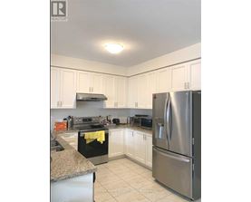 A kitchen with a stainless steel refrigerator and white cabinets.