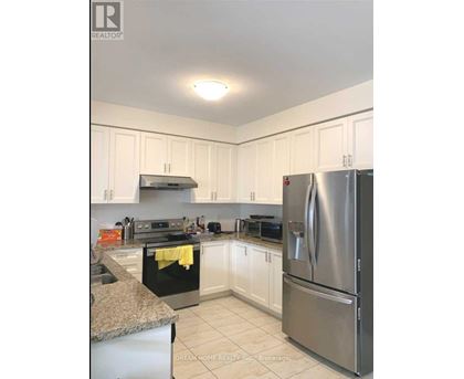 A kitchen with a stainless steel refrigerator and white cabinets.