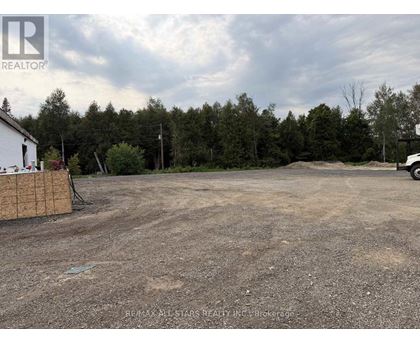 A REALTOR® logo is on a sign in front of a dirt lot.